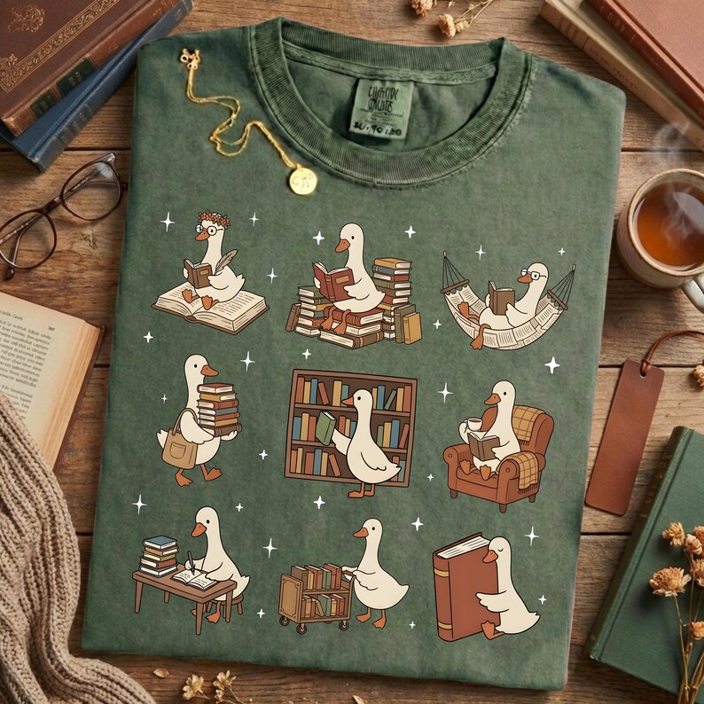 Puede incluir: Camiseta verde con un dise&ntilde;o caprichoso de gansos leyendo libros en varios escenarios. Los gansos est&aacute;n representados con gafas y accesorios, rodeados de libros y estrellas. La camiseta tiene un aspecto vintage, con el texto "Cotton Online" en la etiqueta.