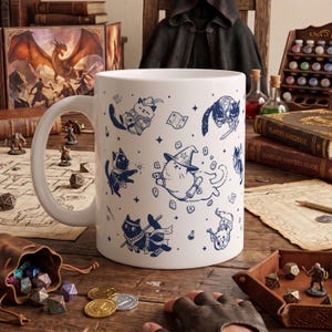 May include: A white ceramic mug featuring a repeating pattern of blue line-art illustrations depicting cats dressed as fantasy role-playing characters, including a wizard, a rogue, and a bard, surrounded by small stars and magical runes.