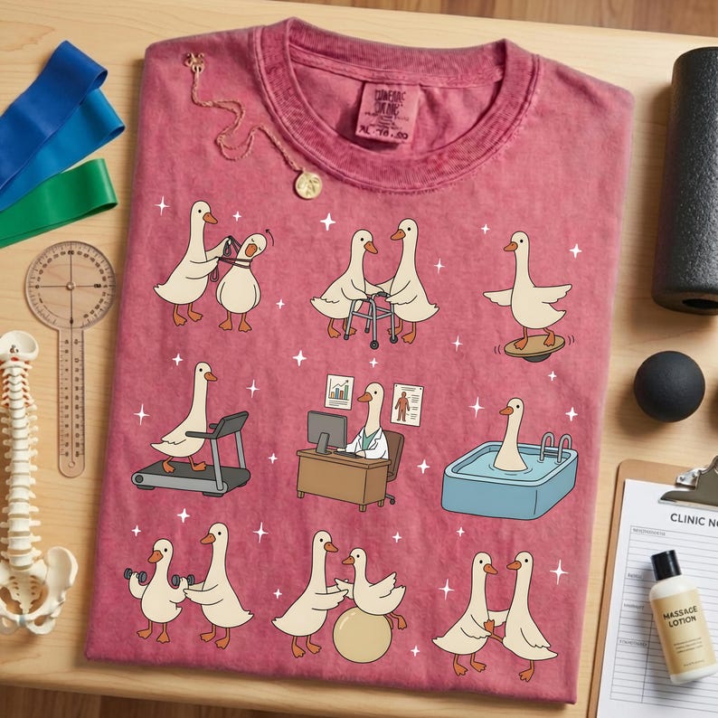 Pode incluir: Camiseta vermelha com gansos de desenho animado em cen&aacute;rios de fisioterapia. Os gansos s&atilde;o retratados usando uma esteira, uma prancha de equil&iacute;brio e halteres. Um colar de ouro e ferramentas m&eacute;dicas tamb&eacute;m s&atilde;o vis&iacute;veis.