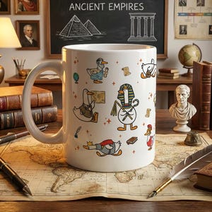 May include: A white ceramic mug featuring a repeating pattern of cartoon ducks dressed as historical figures, including an Egyptian pharaoh, a Roman soldier, and a scholar, interspersed with small orange stars and historical icons.