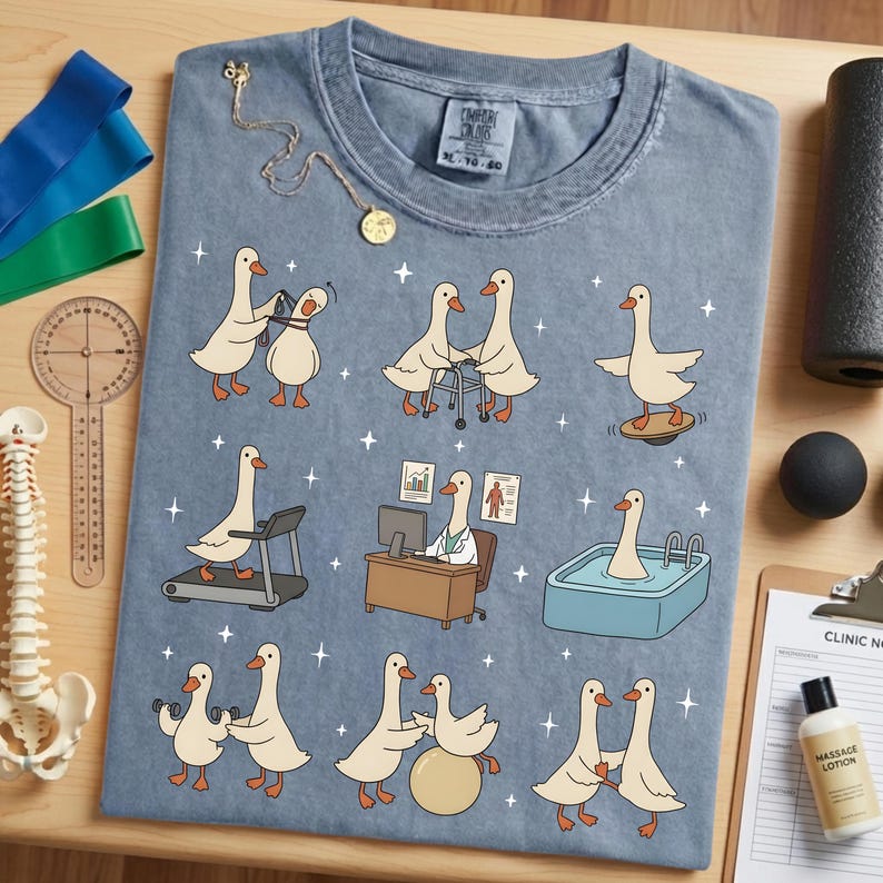 Pode incluir: Uma camiseta Comfort Colors azul clara com gansos de desenho animado em v&aacute;rios cen&aacute;rios de fisioterapia. Os gansos s&atilde;o retratados usando uma esteira, equilibrando-se e usando pesos. A camisa tamb&eacute;m tem uma etiqueta pequena.