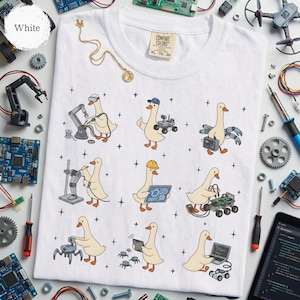 May include: White t-shirt with a playful design featuring cartoon geese in various engineering roles. The geese are depicted with tools, robots, and circuit boards. The shirt has a Comfort Colors tag, size XL 70-50.