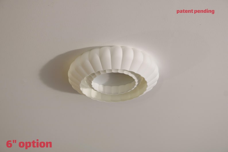 This is a white, 3d printed light shade that mounts onto 4 inch recessed lights. It diffuses the light beautifully, changing the harsh overhead light of recessed lighting into a soft glow, and provides a beautiful decorative touch as well. It has an elegant, scalloped edge and which has floral feeling to it. No hardware is needed to install the light, it comes with easy-to-install tabs that make install or changing a bulb simple.
