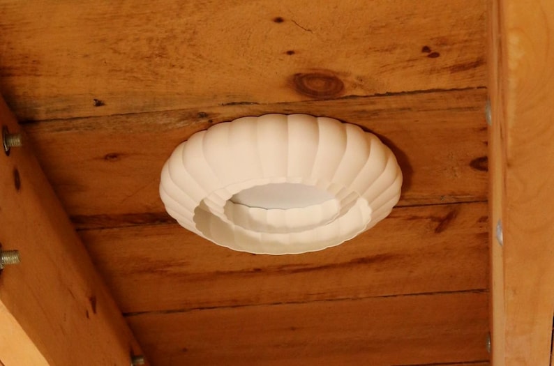 This is a white, 3d printed light shade that mounts onto 6 inch recessed lights. It diffuses the light beautifully, changing the harsh overhead light of recessed lighting into a soft glow, and provides a beautiful decorative touch as well. It has an elegant, scalloped edge and which has floral feeling to it. No hardware is needed to install the light, it comes with easy-to-install tabs that make install or changing a bulb simple.