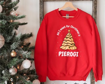 Może przedstawiać: Czerwona bluza unisex z białym napisem "All I want for Christmas is Pierogi". Grafika przedstawia choinkę w kształcie pieroga z gwiazdą na górze. Na dole nadruk "Unisex Sweatshirt".