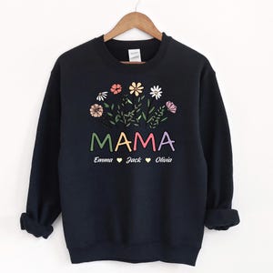 May include: Black sweatshirt featuring a floral design and the word "MAMA" in rainbow colours. Below the word "MAMA" are the names "Emma", "Jack", and "Olivia" with hearts between each name.