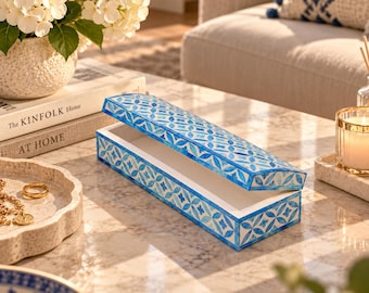 May include: A rectangular decorative box with a hinged lid featuring a blue and white geometric floral pattern. The box has a smooth finish and is open, revealing a plain white interior. The exterior surfaces are covered in a repeating motif.