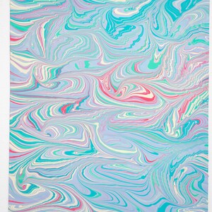 May include: Abstract art print with a marbled design. The artwork features swirling patterns in shades of blue, teal, pink, and white. The paper has a textured appearance, with visible edges. The overall aesthetic is reminiscent of water or clouds.