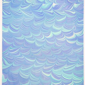 May include: A rectangular sheet of paper with a marbled design. The pattern features flowing, wave-like swirls in shades of blue, teal, and white. The edges of the paper are slightly uneven, suggesting a handmade quality.