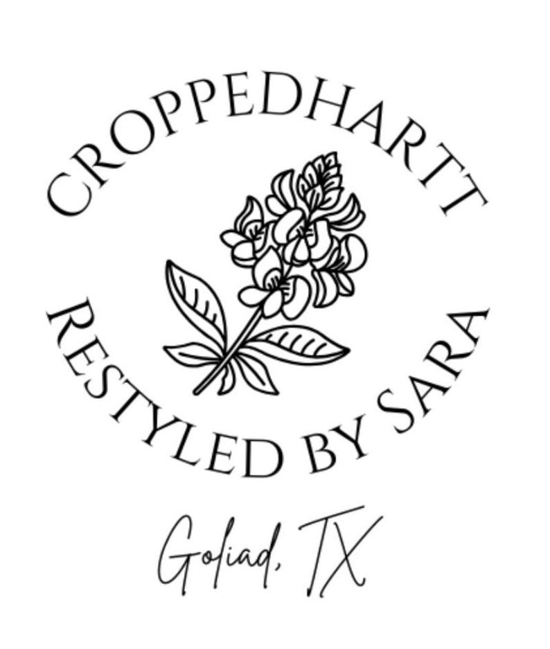 May include: A black and white logo with the text "CROPPEDHARTT RESTYLED BY SARA" encircling a floral illustration. Below the circle is the text "Goliad, TX". The design is simple and elegant.