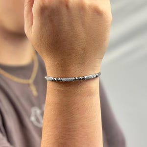 May include: A silver bracelet with black beads and small clear stones.