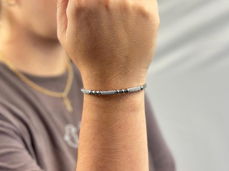 May include: A silver bracelet with black beads and small clear stones.