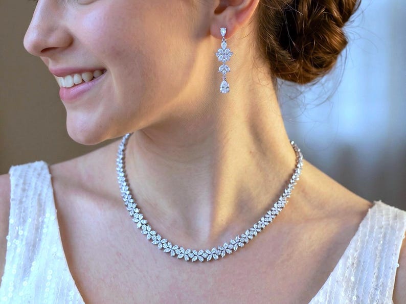 a stunning silver necklace with CZ crystals with a leaf pattern and matching dangling earrings that feature three patterns leading to a teardrop on a beautiful bride