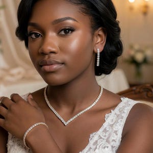 May include: A woman wearing a diamond necklace, bracelet, and earrings. The jewellery is set against a white dress with lace detailing. The background features soft lighting and floral arrangements.