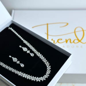 a stunning silver necklace with a leaf pattern and matching dangling earrings that feature three patterns leading to a teardrop