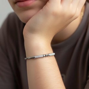 A silver bangle bracelet with small round stones and a row of smaller stones.