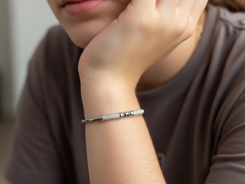 A silver bangle bracelet with small round stones and a row of smaller stones.