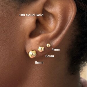 May include: Three 18K solid gold ball stud earrings in graduated sizes. The earrings are labeled with their respective diameters of 4mm, 6mm, and 8mm. The polished gold spheres have a smooth, reflective surface and are worn in a single earlobe.