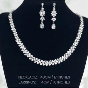 a stunning silver necklace with a leaf pattern and matching dangling earrings that feature three patterns leading to a teardrop. Necklace is 43cm/17inches and earring is 4cm/1.6inches