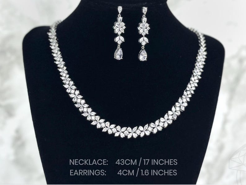 a stunning silver necklace with a leaf pattern and matching dangling earrings that feature three patterns leading to a teardrop. Necklace is 43cm/17inches and earring is 4cm/1.6inches