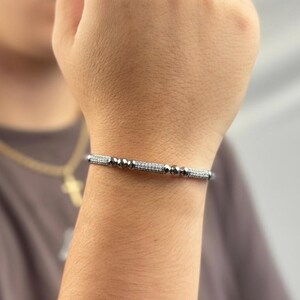 A silver bangle bracelet with small round stones and a row of smaller stones.
