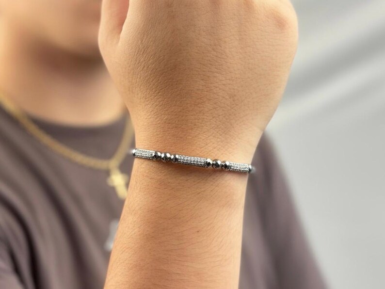 A silver bangle bracelet with small round stones and a row of smaller stones.