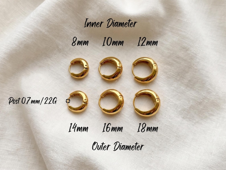 Gold-colored hoop earrings, 8mm, 10mm 12mm inner diameter size with their outer diameter being 15, 16, and 18mm respectively, are displayed on a soft ivory cream fabric. The image is a close-up, highlighting the jewelry's design and shine. Earring post diameter is 0.7mm/22G