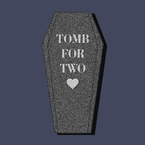 May include: A black coffin-shaped box with the text "TOMB FOR TWO" and a white heart in the center.