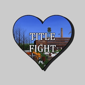 May include: A heart-shaped graphic with a blue sky and a brick building with a water tower. The text "TITLE FIGHT" is in white letters on the building. There is a fire and debris in the foreground.
