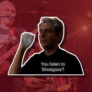 Puede incluir: Un hombre con cabello oscuro y una camisa negra sostiene un cigarrillo y mira a la c&aacute;mara. El texto "You listen to Shoegaze?" est&aacute; escrito en blanco sobre un fondo negro.