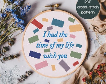 May include: A cross-stitch embroidery hoop with the text "I had the time of my life with you" in blue. The design includes colorful rectangular shapes. The text "PDF cross-stitch pattern" is in a circle in the upper right corner.