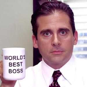 May include: A man with dark hair and a white shirt is holding a white mug with the text "WORLD'S BEST BOSS" in black lettering.
