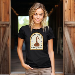 May include: Black t-shirt with a yellow and brown graphic of a glass flask with the text "Distilling Good Times One Whiskey at a Time".