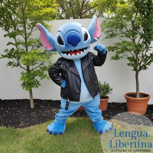 May include: A blue character costume with large ears, wearing a black leather jacket and blue pants. The character has a large head and a wide grin. The costume is standing on green grass with trees in the background.