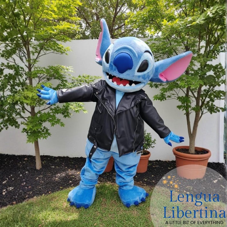 May include: A blue character costume with large ears, wearing a black leather jacket and blue pants. The character has a wide smile and is standing in front of green trees. The costume has blue hands and feet.