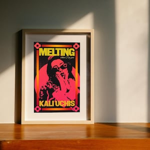 May include: A framed poster with a black background and a pink and yellow graphic of a woman with sunglasses and the text "MELTING when I see you" and "KALI UCHIS".
