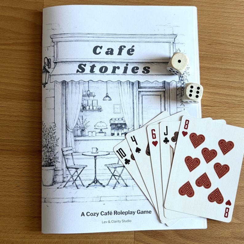 Printable cozy café journaling game with cards and dice on a wooden table