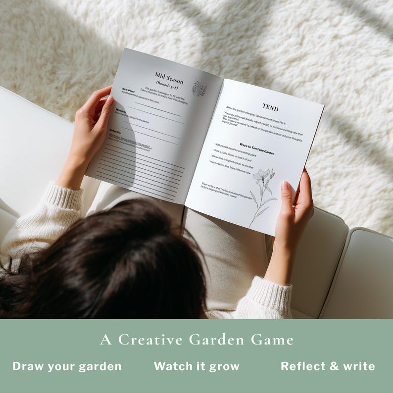 May include: A person holding open a journal with the text "Mid Season" and "TEND" visible. The journal is part of "A Creative Garden Game" and includes prompts to "Draw your garden", "Watch it grow", and "Reflect & write".