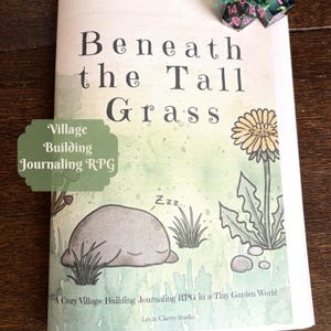 Könnte beinhalten: Ein Softcover-Buch mit dem Titel Beneath the Tall Grass, A Cozy Village-Building Journaling RPG in a Tiny Garden World von Lev & Clarity Studio. Das Cover zeigt einen schlafenden grauen Stein, einen gelben Löwenzahn und grünes Gras.
