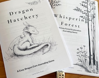 May include: Two open books with black and white illustrations and text. One book is titled "Dragon Hatchery" with a dragon illustration. The other book is titled "Whispering Forest." Two dice are in the foreground. The books are labeled "A Cozy Dragon Care Journaling Game" and "A Cozy Forest Exploration Journaling Game."