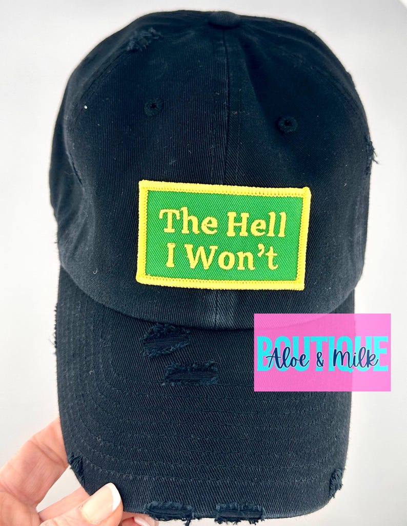 May include: Black distressed baseball cap with a green and yellow patch that reads "The Hell I Won't".