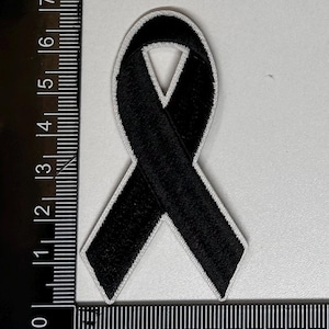 May include: Black ribbon patch with white stitching, measuring approximately 2 inches wide and 3 inches long.