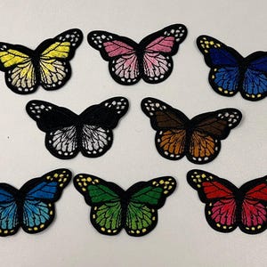 May include: Assortment of ten embroidered iron-on butterfly patches in various colors, including yellow, pink, blue, black, brown, green, and red.