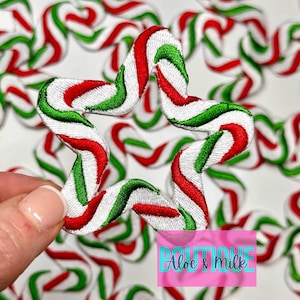 May include: Red, white, and green candy cane star-shaped patches. The patches are made of fabric and have a stitched design.