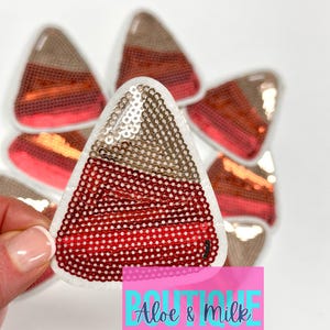 May include: A set of six red, gold, and white candy corn shaped iron-on patches with sequins. The patches are approximately 2 inches tall.