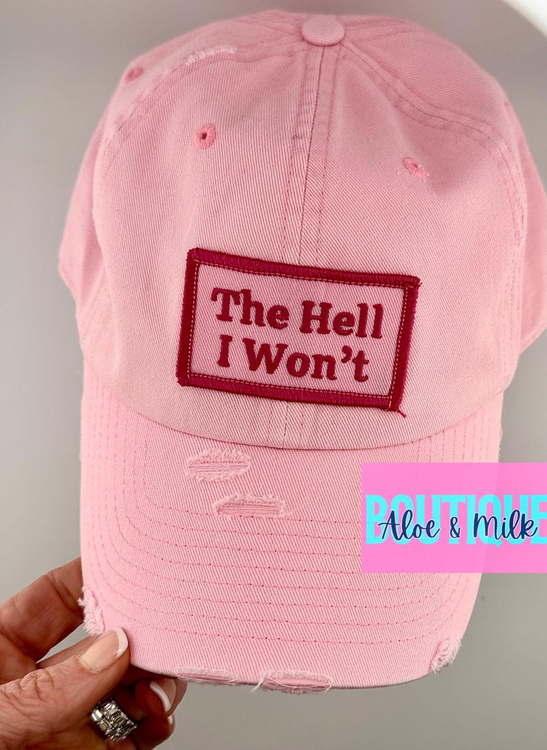 May include: Pink distressed baseball cap with a red patch that says "The Hell I Won't".
