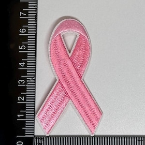 May include: Pink ribbon embroidered patch. The ribbon is a symbol of breast cancer awareness.
