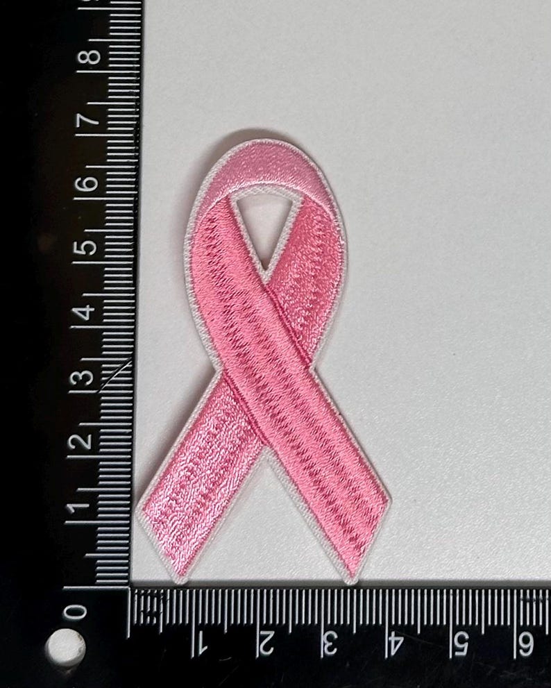 May include: Pink ribbon embroidered patch. The ribbon is a symbol of breast cancer awareness.