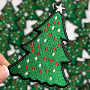 May include: Green felt Christmas tree patch with red and white embroidered lights and a white star on top.