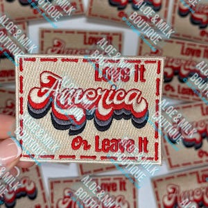 May include: A beige embroidered patch with red, white, and blue lettering that reads "Love it America or Leave it".
